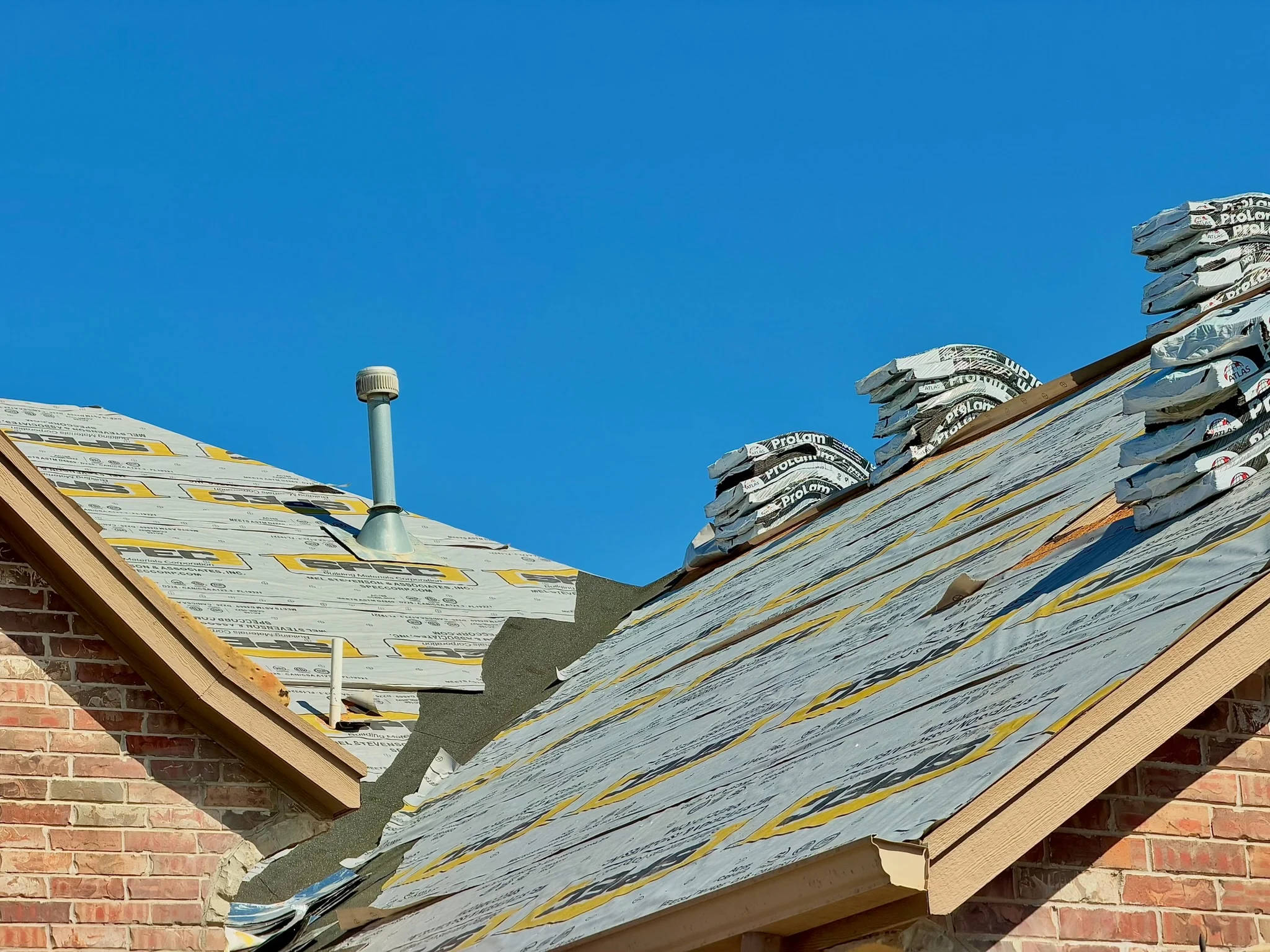 Roof replacement in progress showing underlayment and material staging